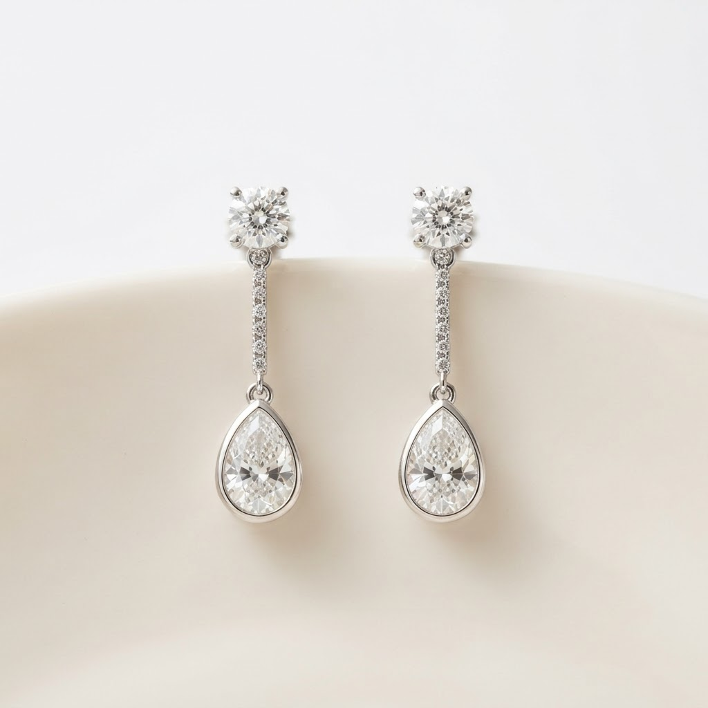 A pair of diamond drop earrings on an ivory surface